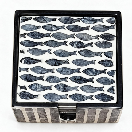 Handcrafted mother-of-pearl coasters with elegant navy fish pattern, styled with a refreshing citrus drink.