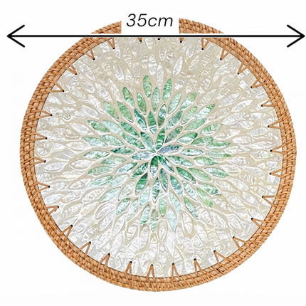 A round rattan placemat showcasing a distinctive botanical leaf burst design inspired by the natural beauty of coastal living.