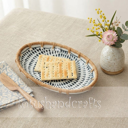 Elegant oval ceramic tray featuring a bold monochrome spiral pattern framed by natural rattan.