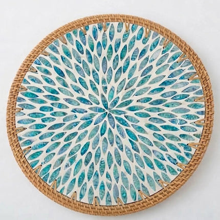 Handcrafted turquoise blue leaf burst placemat featuring a mesmerizing radial pattern and natural rattan border.