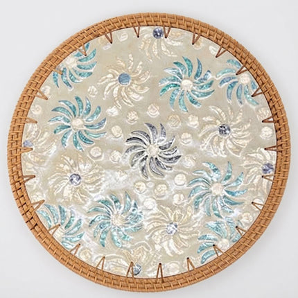 Blue green sunburst floral rattan charger plate featuring intricate swirling flower patterns and shimmering mother of pearl details.