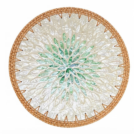 A handcrafted round Mother of Pearl rattan placemat featuring an elegant emerald green leaf burst pattern at the centre.