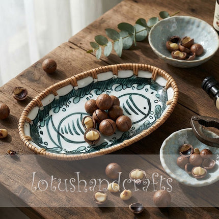 Close-up of the decorative oval ceramic tray showcasing detailed twin fish artwork and handcrafted woven rattan border.