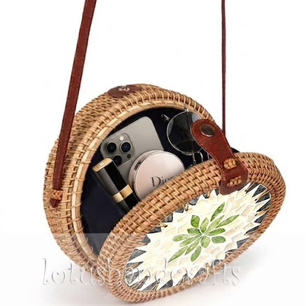 This exquisite round rattan crossbody bag features a mother of pearl leaf mosaic and leather strap.