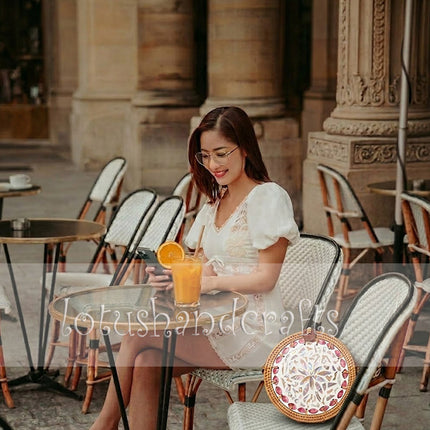 Unique round rattan crossbody bag adorned with pink petal mother of pearl inlay.