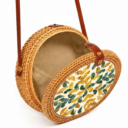 Round rattan crossbody bag with green and yellow mother of pearl leaf inlay that attracts every eye.