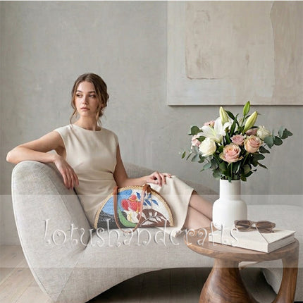 The elegant woven grass half moon bag beautifully showcases a delicate painted lady motif.