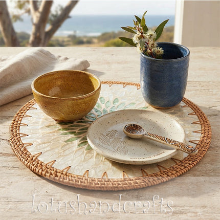 Elegant handcrafted table décor combining radiant Mother of Pearl, emerald botanical leaves and natural woven rattan texture.