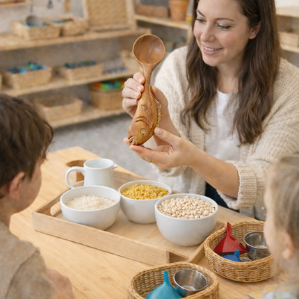 Cute hand carved wooden fish spoon used in Montessori school activities, supporting natural learning and sensory development for young children.