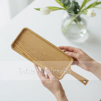 Long ash wood serving board with handle is easy to clean and maintain.