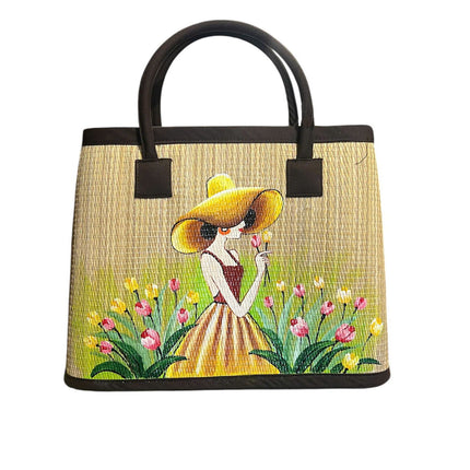 Handwoven seagrass tote bag with a charming hand-painted girl in a tulip garden.