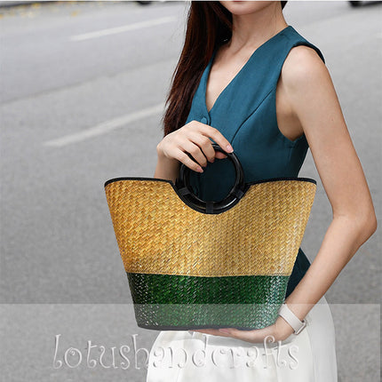 Handwoven seagrass tote bag with round black handles in natural and forest green.