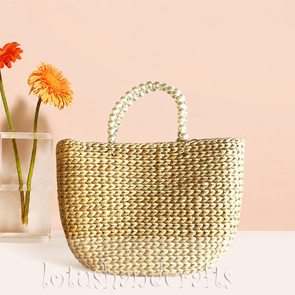 Handwoven water hyacinth tote bag with elegant pearl handles.
