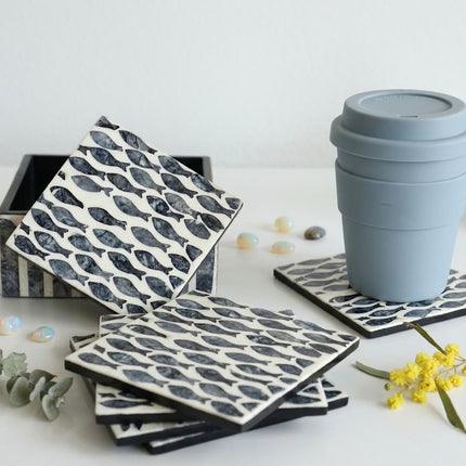 Set of drink coasters with intricate fish inlay, black-edged finish, ideal modern classic decor.