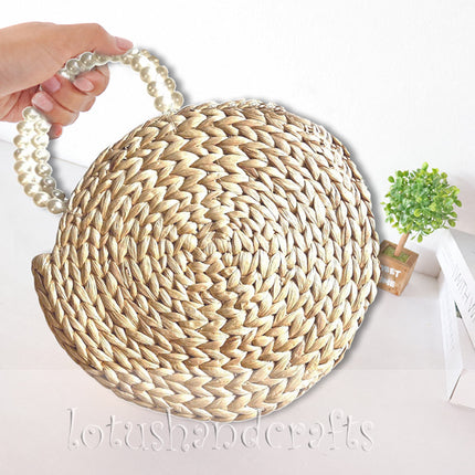 Handwoven round water hyacinth handbag with faux pearl handle style.