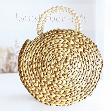 Handwoven round water hyacinth handbag with a faux pearl handle.