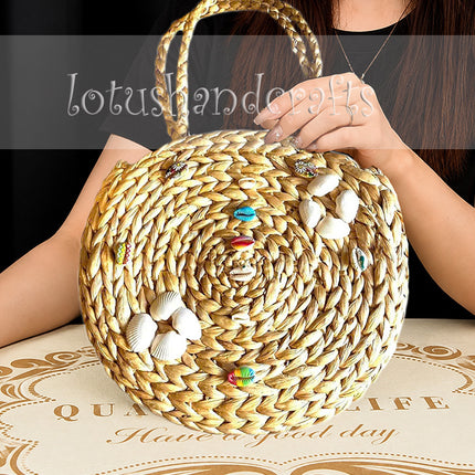 Boho round water hyacinth tote with seashell embellishments for stylish women.
