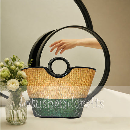 Stylish handwoven seagrass tote bag with round black handles in natural and forest green.