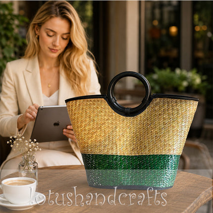 Handwoven seagrass tote bag with round black handles in natural and forest green.