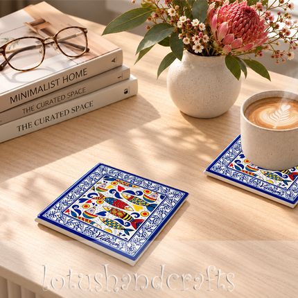 Decorative sardine ceramic coaster with golden-yellow scales, vivid red patterns, and deep cobalt blue accents against a cream background.
