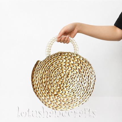 Handwoven round water hyacinth handbag with faux pearl handle in boho style.