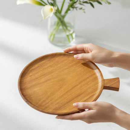 Handcrafted round wooden serving plate with handle made from natural wood.